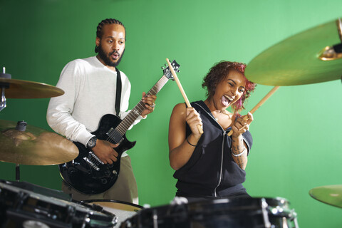 Studenten spielen Gitarre und Schlagzeug im Musikraum der Hochschule, lizenzfreies Stockfoto