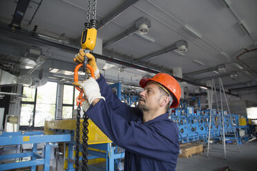 Arbeiter beim Einstellen eines Kettenzugs in einer Industrieanlage - CUF36903