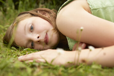 Close up portrait of girl lying on garden grass - CUF36913