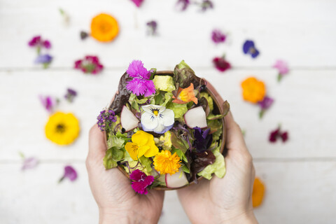Frauenhände halten Schüssel mit Salat mit essbaren Blumen, lizenzfreies Stockfoto
