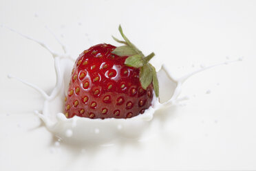 Fresh strawberry splashing onto milk surface - CUF36962