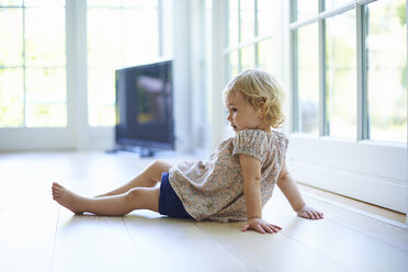Portrait female toddler sitting on living room floor - CUF36975