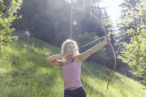 Bogenschützin zielt mit ihrem Bogen, lizenzfreies Stockfoto