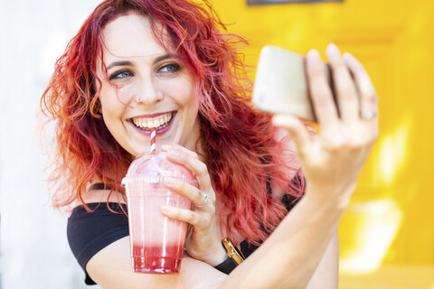 Portrait of laughing woman taking selfie with smartphone while drinking smoothie stock photo