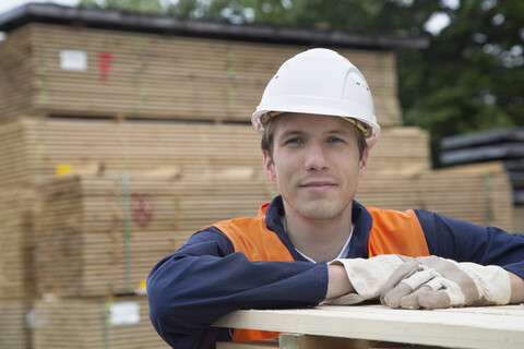 Porträt eines jungen Arbeiters auf einem Holzlagerplatz, lizenzfreies Stockfoto