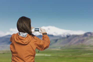 Woman taking picture with smartphone of Snaefellsnes glacier, Iceland - CUF37068