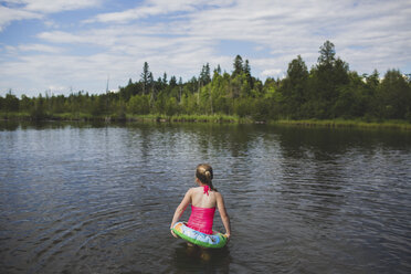 Rear view of girl with rubber ring in Indian river, Ontario, Canada - CUF37071