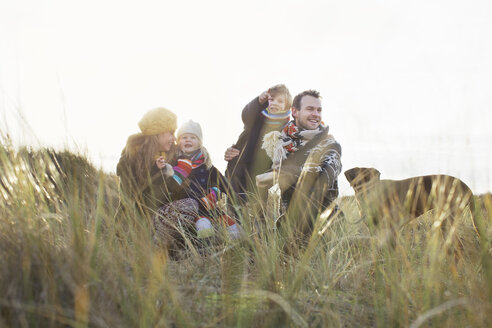 Mid adult couple in sand dunes with their son, daughter and dog - CUF37128