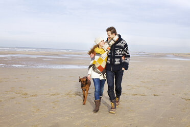 Mittleres erwachsenes Paar und Hund spazieren am Strand, Bloemendaal aan Zee, Niederlande - CUF37137