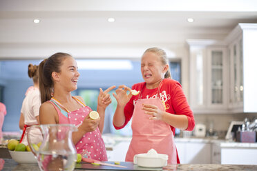 Zwei Teenager-Mädchen probieren in der Küche saure Zitronen - CUF37144