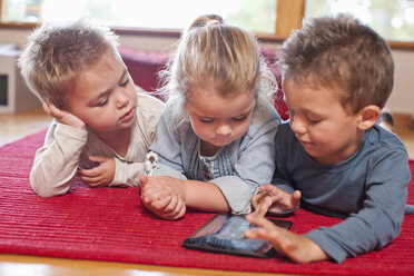 Zwei Jungen und ein Mädchen benutzen ein digitales Tablet in der Vorschule - CUF37151