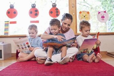 Lehrerin und Schüler lesen im Kindergarten Geschichten vor - CUF37152