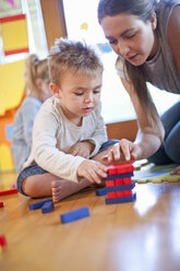 Teacher and boy constructing building blocks at nursery school - CUF37160