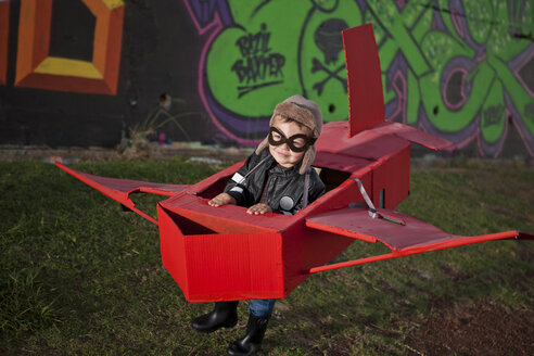 Junge mit Flugbrille, der in einem Spielzeugflugzeug im nächtlichen Park läuft - CUF37161