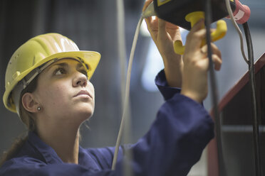 Female engineer checking valves and cables in factory - CUF37186