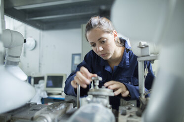 Ingenieurin dreht Ventile an industriellen Rohrleitungen in einer Fabrik - CUF37188