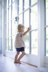 Portrait female toddler looking out of patio doors - CUF37258