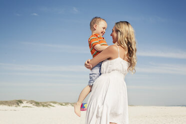 Mid adult mother carrying son on beach, Cape Town, Western Cape, South Africa - CUF37344