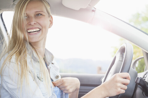 Junge Frau lächelnd hinter dem Steuer eines Autos, lizenzfreies Stockfoto