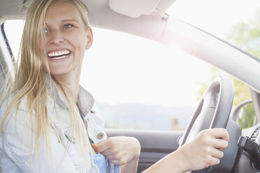 Young woman smiling behind wheel of car - CUF37366