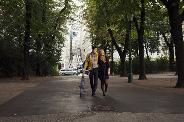 Young couple strolling in tree lined park - CUF37381