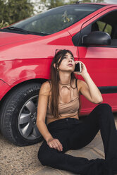 Junge Frau, die am Straßenrand sitzt und eine Autopanne hat, ruft den Pannendienst an - ACPF00060