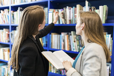 Two teenage girl in a public library choosing books - WPEF00499