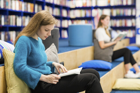 Teenager-Mädchen sitzen in einer öffentlichen Bibliothek und lesen ein Buch - WPEF00508