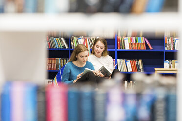 Zwei Mädchen im Teenageralter sitzen in einer öffentlichen Bibliothek und lesen Bücher - WPEF00510