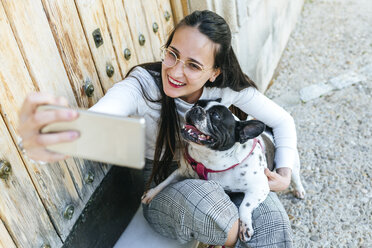 Young woman using smartphone, taking a selfie with her dog - KIJF01955