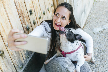 Junge Frau mit Smartphone, die ein Selfie mit ihrem Hund macht - KIJF01956