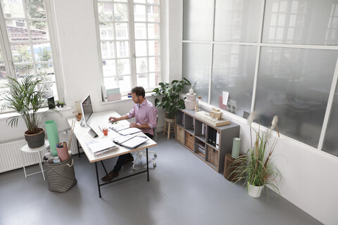 Man working at desk in a loft office stock photo