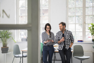 Colleagues using tablet in a loft office - FKF02956