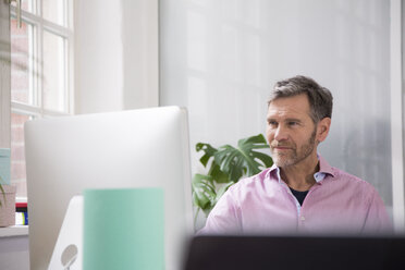 Portrait of a man working at desk in office - FKF02959