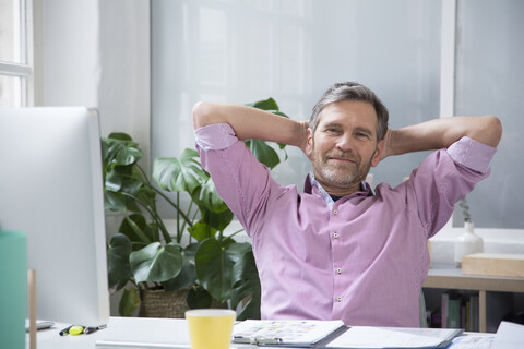 Porträt eines selbstbewussten Mannes am Schreibtisch im Büro, lizenzfreies Stockfoto