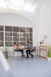 Colleagues sitting at table in an architect's loft office - FKF02985