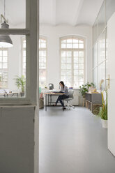 Woman working at desk in a loft office - FKF03008