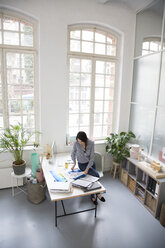 Woman working at desk in a loft office - FKF03020