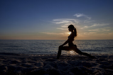 Silhouetted young woman practicing yoga at sunset, Oristano, Sardinia, Italy - CUF37581