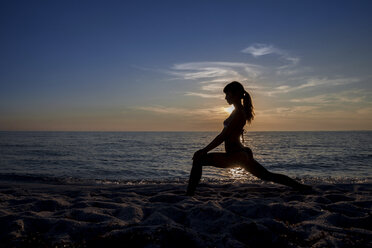 Silhouettierte junge Frau, die bei Sonnenuntergang Yoga praktiziert, Oristano, Sardinien, Italien - CUF37581