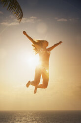 Silhouette of young woman jumping mid air in sunset over sea, Etosha National Park, Namibia - CUF37595