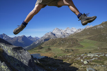 Beine eines männlichen Wanderers, der über Felsen springt, Lai da Fons, Kanton Graubünden, Schweiz - CUF37598