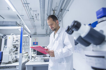 Lab assistant checking details on clipboard - CUF37667