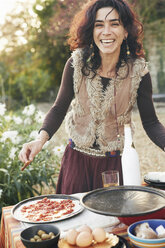 Portrait of mature hippy female preparing pizza in garden - CUF37894