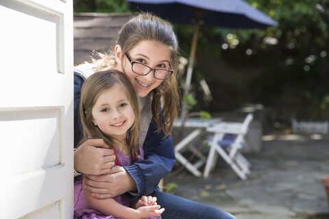 Mädchen, das seine Schwester im Garten umarmt, lizenzfreies Stockfoto