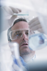 Scientist pouring liquid into measuring beaker - ISF14567