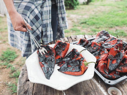 Weibliche Hand hält gegrillte rote Paprika - NOF00037