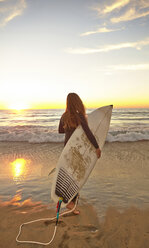 Girl at beach carrying surfboard wearing wetsuit - ISF14592