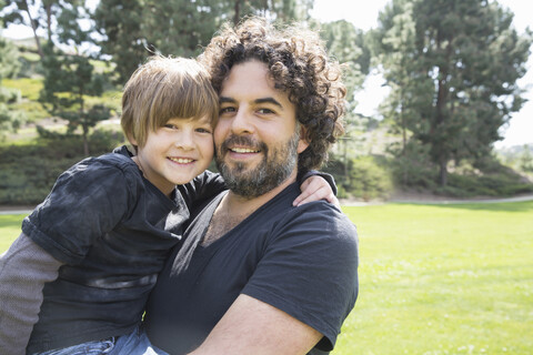 Porträt eines stolzen Vaters und seines Sohnes im Park, lizenzfreies Stockfoto