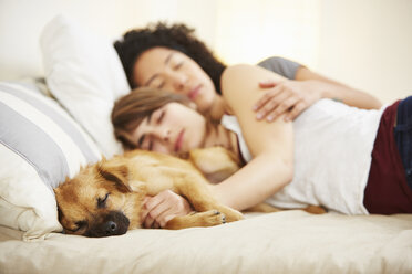 Young female couple and pet dog sleeping on bed - ISF14641